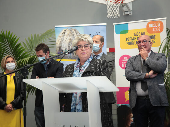 Discours de Mme Lydie Librizzi, présidente de la caisse d'allocations familiales du Nord (CAF) devant un pupitre blanc en arrière plan les élus de la ville de CAMBRAI
